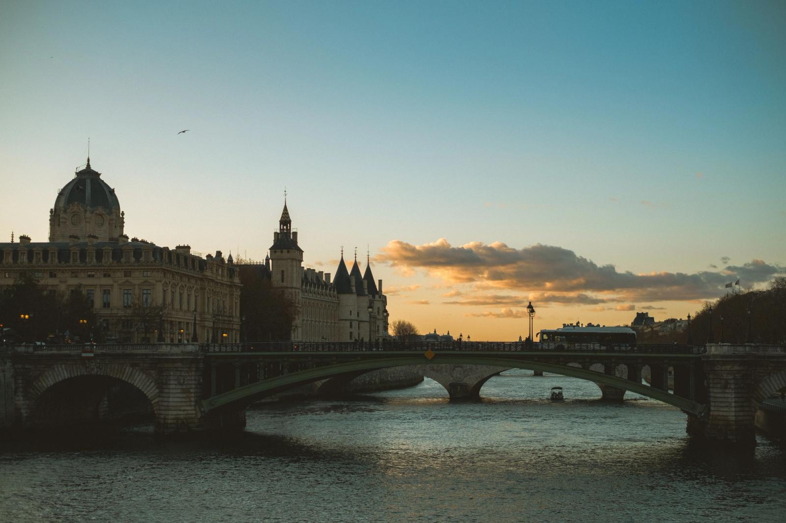 Stunning view of a bridge over Seine River in Paris at sunset, capturing the skyline and river ambiance