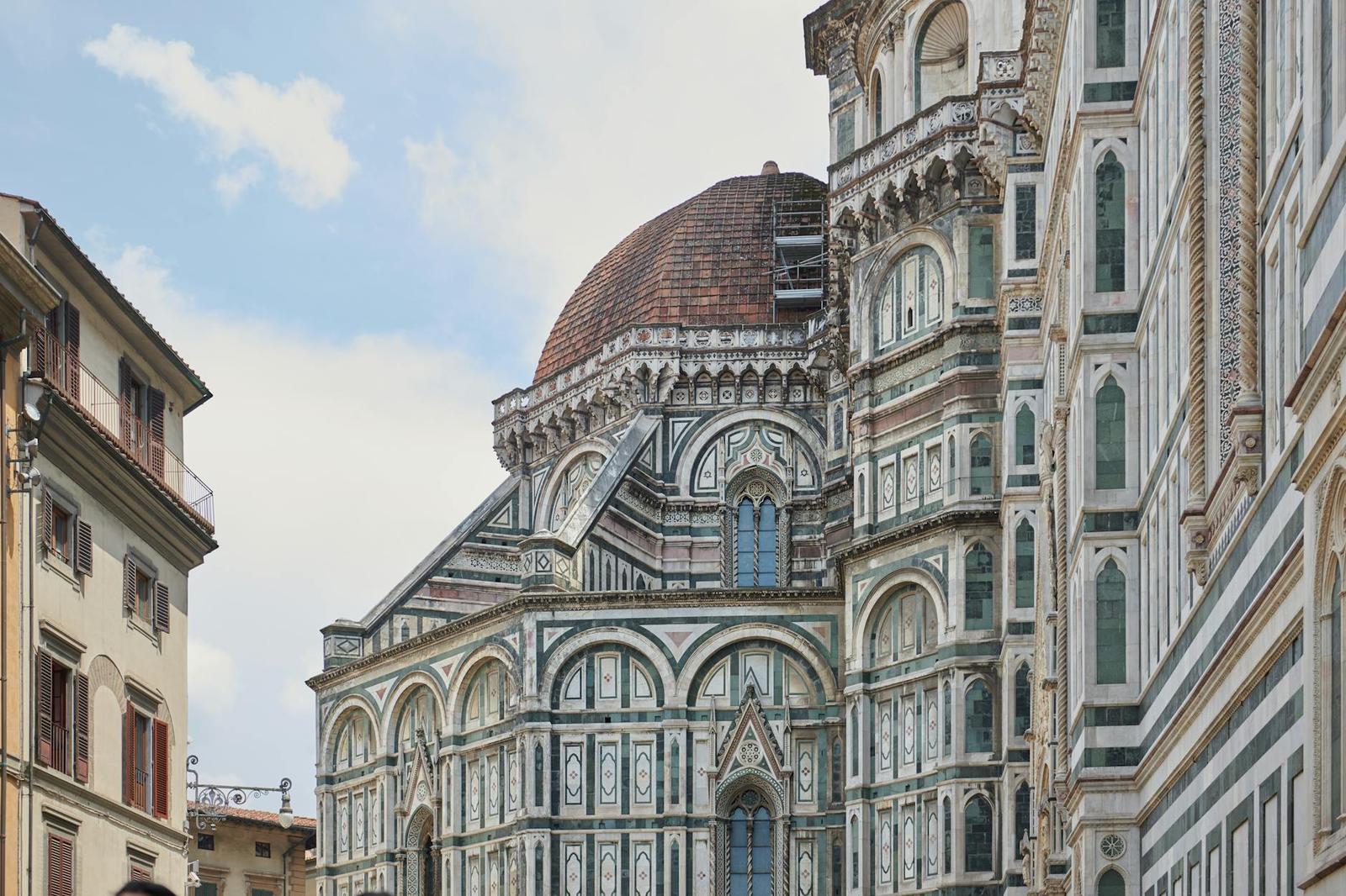 A marble cathedral with an octagonal red-tiled dome rising above narrow city streets