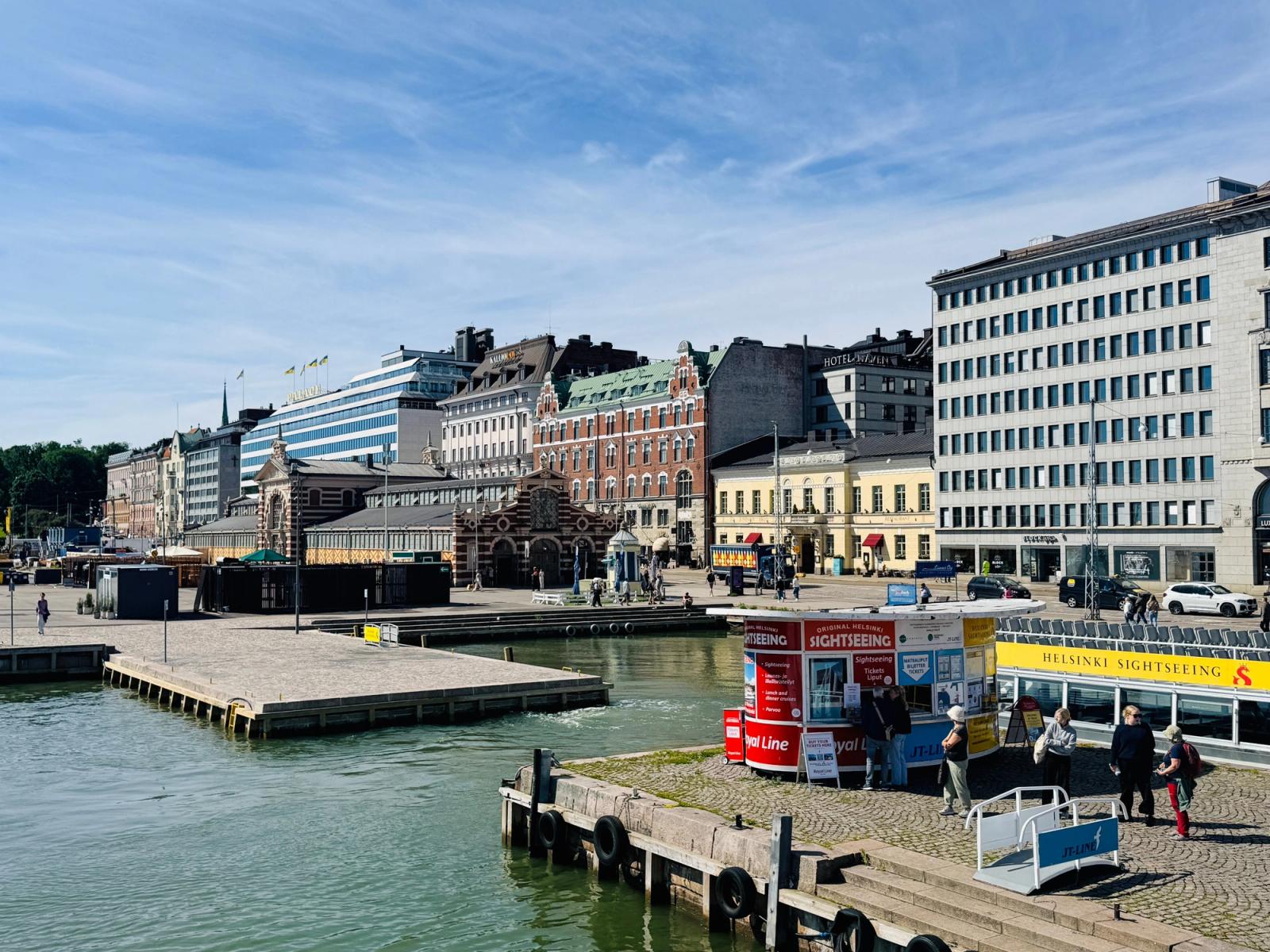 Vibrant day at Helsinki's harbor with historic buildings and sightseeing kiosks