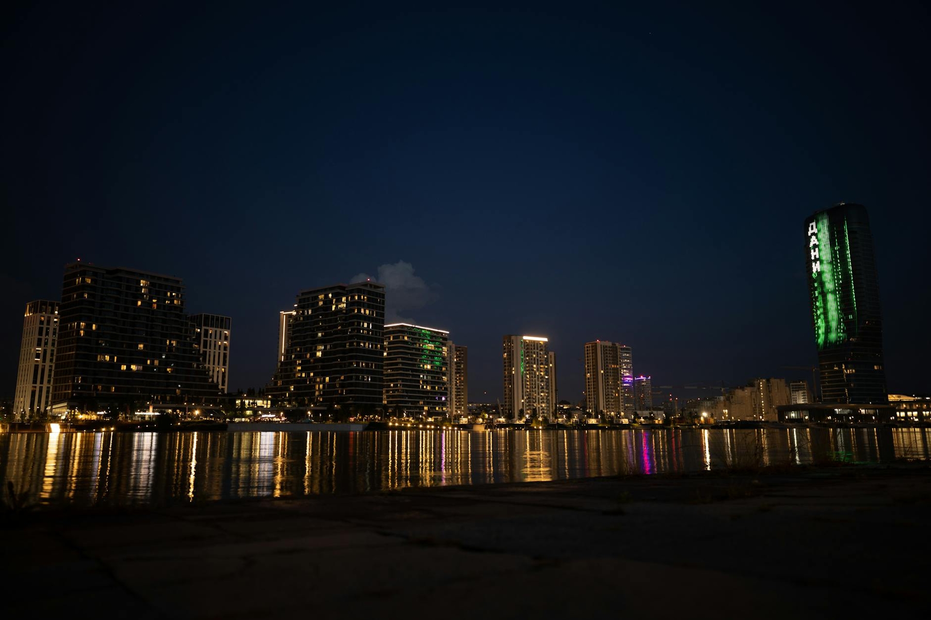 City skyline glowing with lights and reflections along the waterfront at night