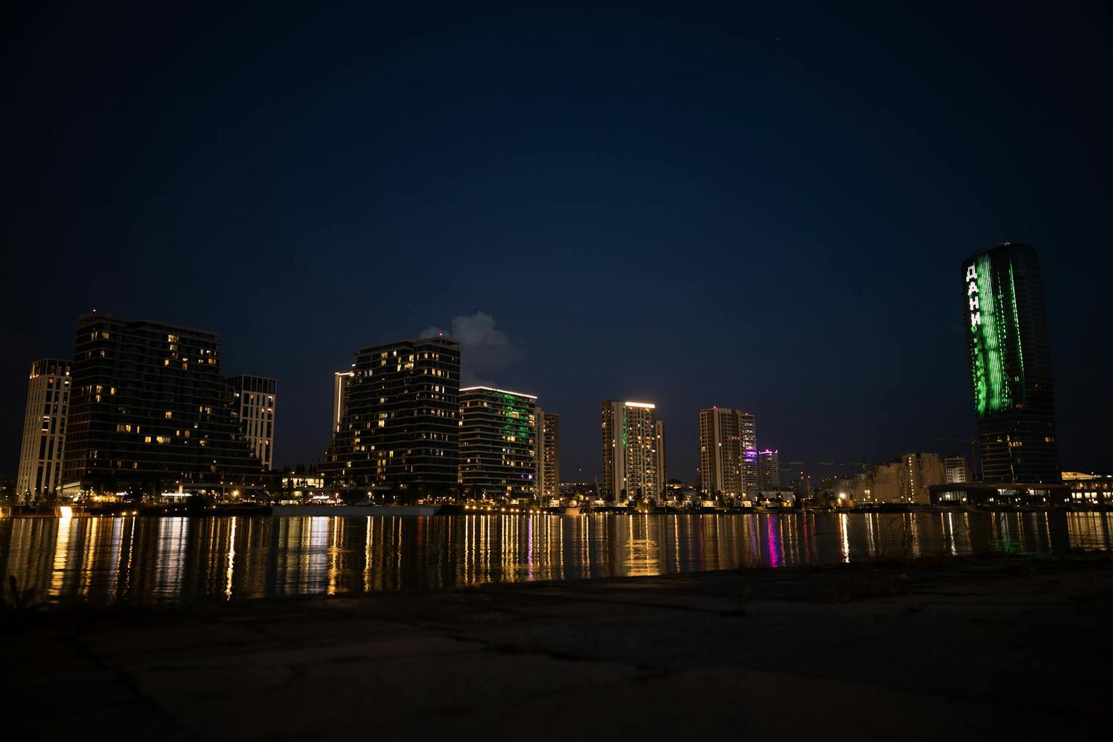 City skyline glowing with lights and reflections along the waterfront at night