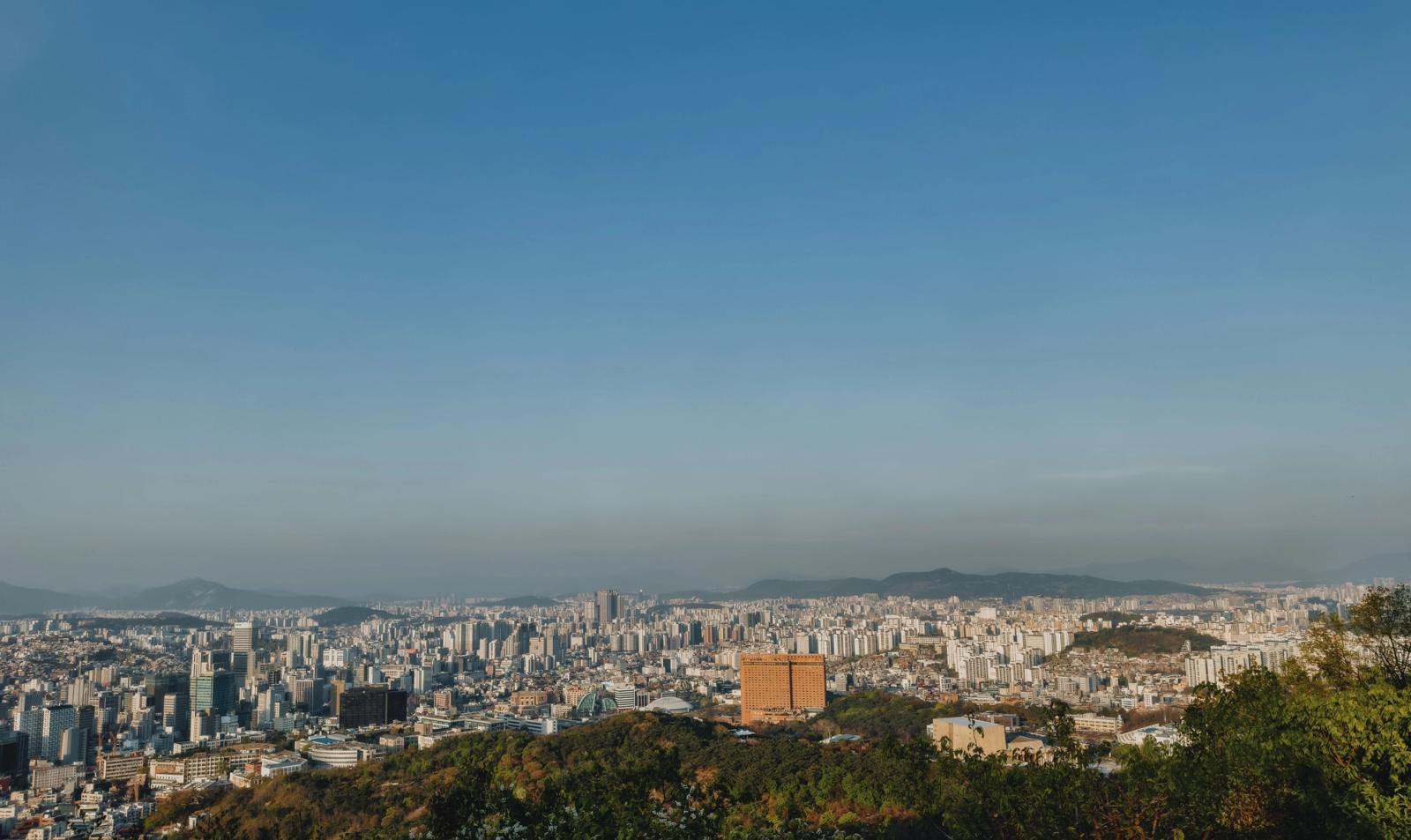 Expansive view of Seoul's skyline from a hilltop with clear blue sky