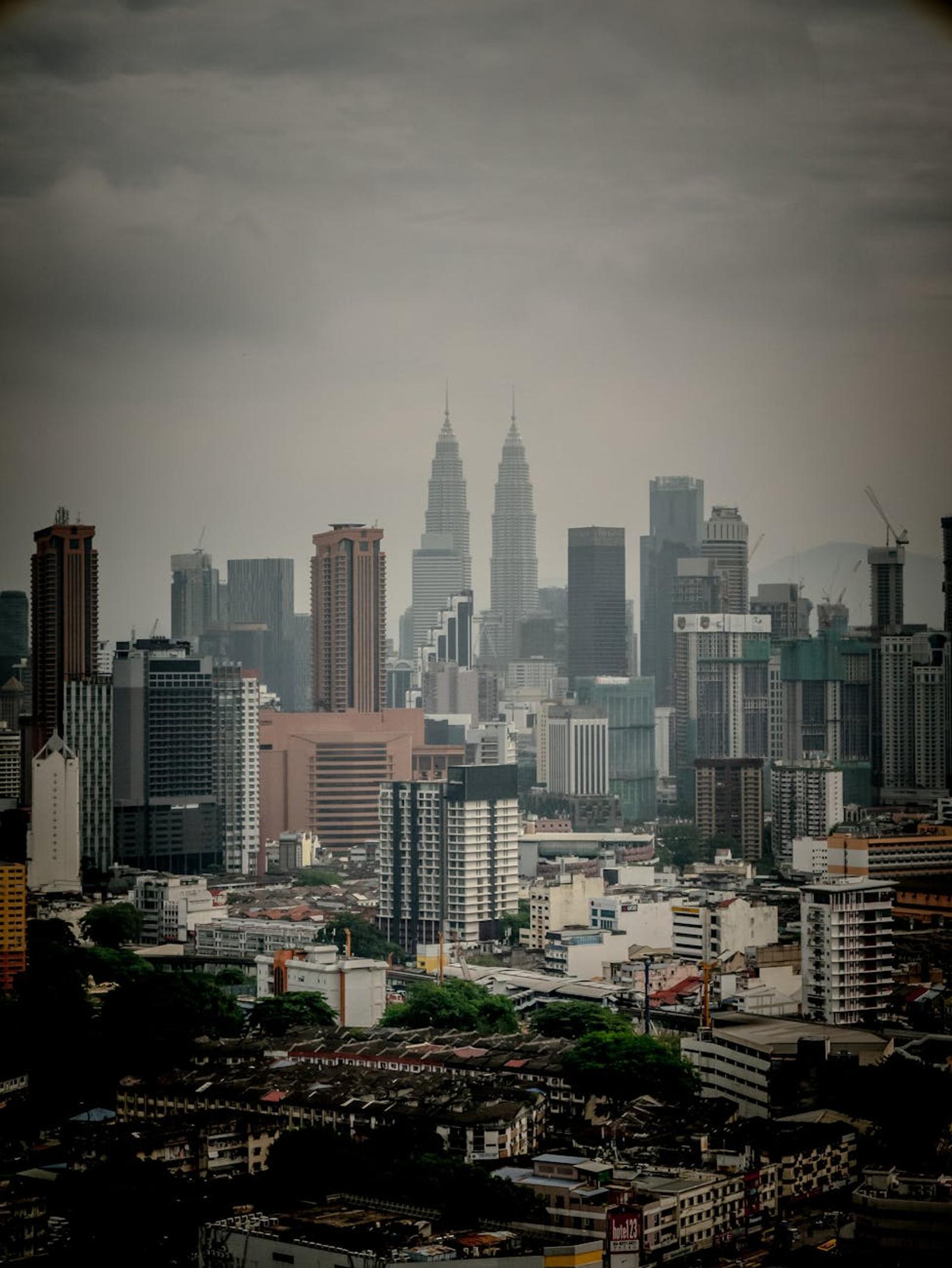 Hazy city skyline with twin towers rising above dense low-rise buildings