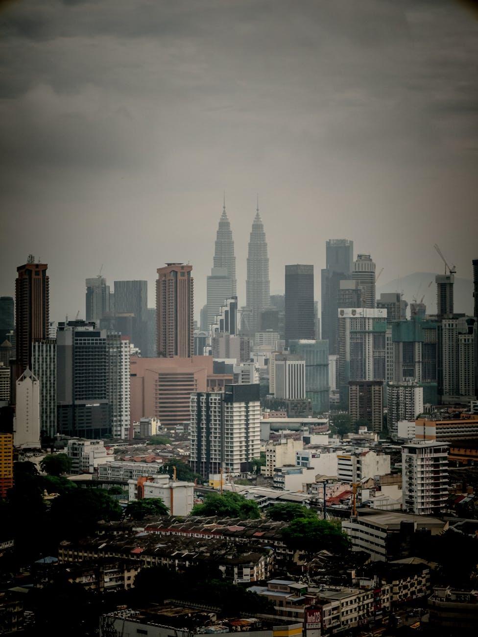 Hazy city skyline with twin towers rising above dense low-rise buildings