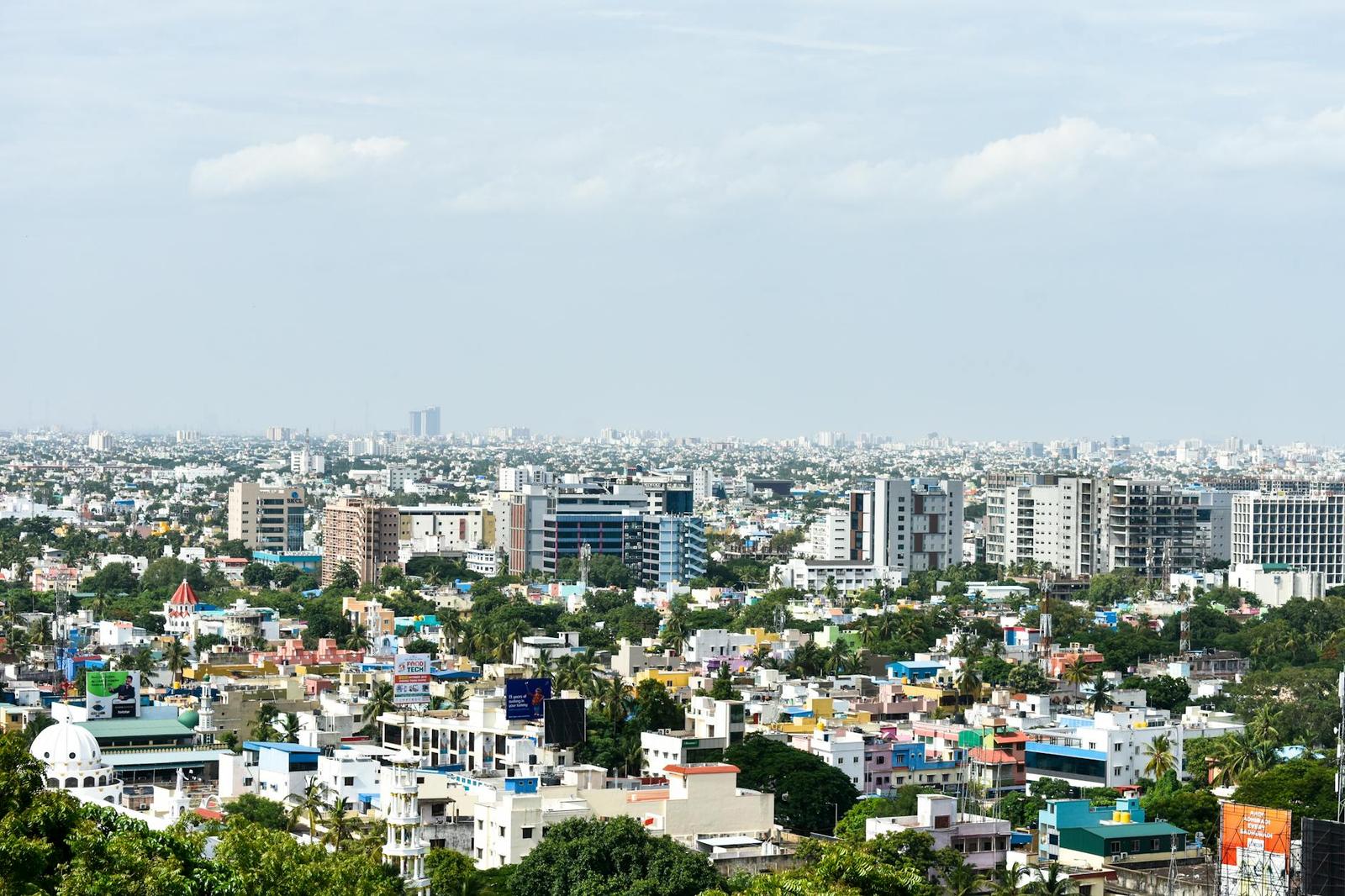 A sprawling city skyline of low-rise buildings under a hazy sky