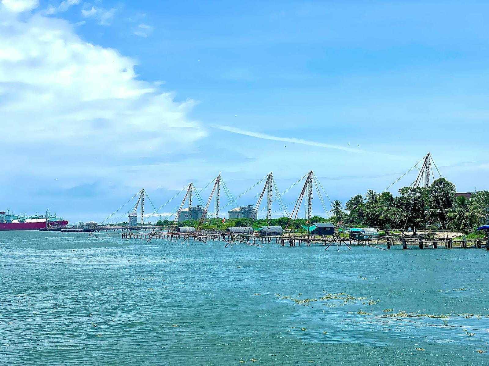 Cantilevered fishing nets along a harbor with a cargo ship passing