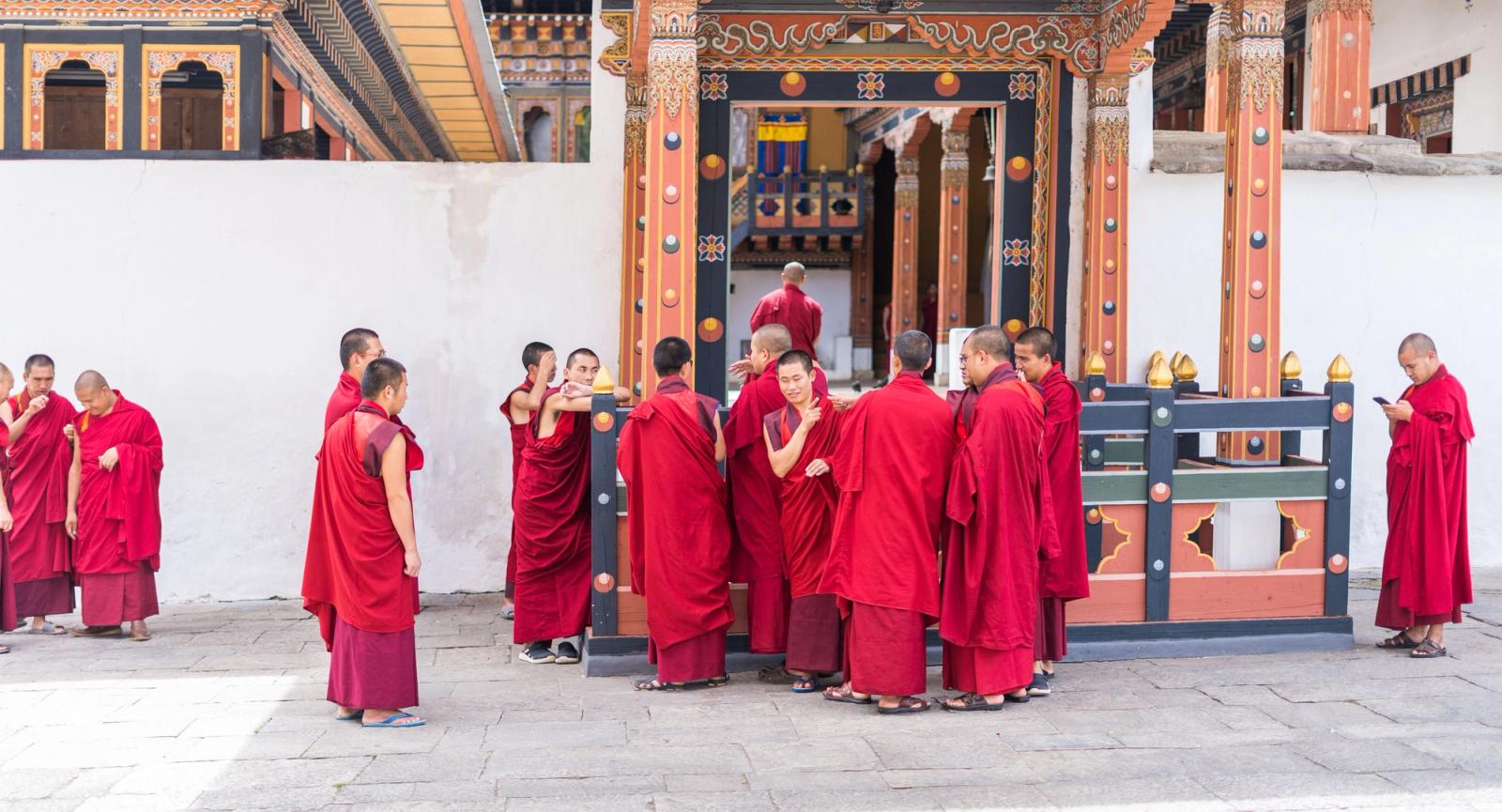 Group of monks in red robes gathered at a temple entrance for a religious ceremony
