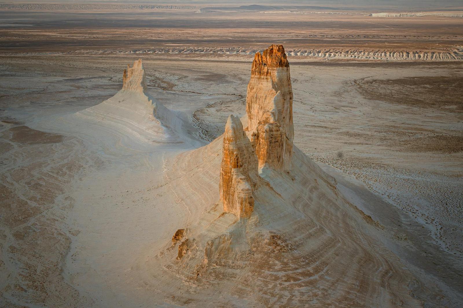 Eroded chalk-coloured rock spires rising from a flat desert plain