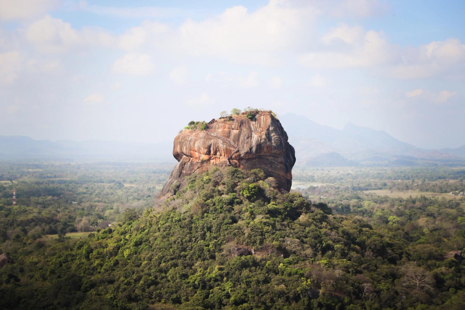 View of the iconic Sigiriya Rock Fortress, surrounded by lush vegetation in Sri Lanka