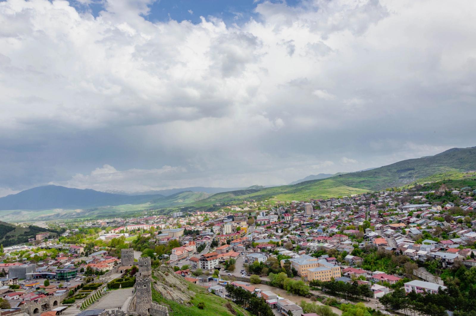 A panoramic view of Gori, Georgia, showcasing its historic architecture and lush landscape under a cloudy sky
