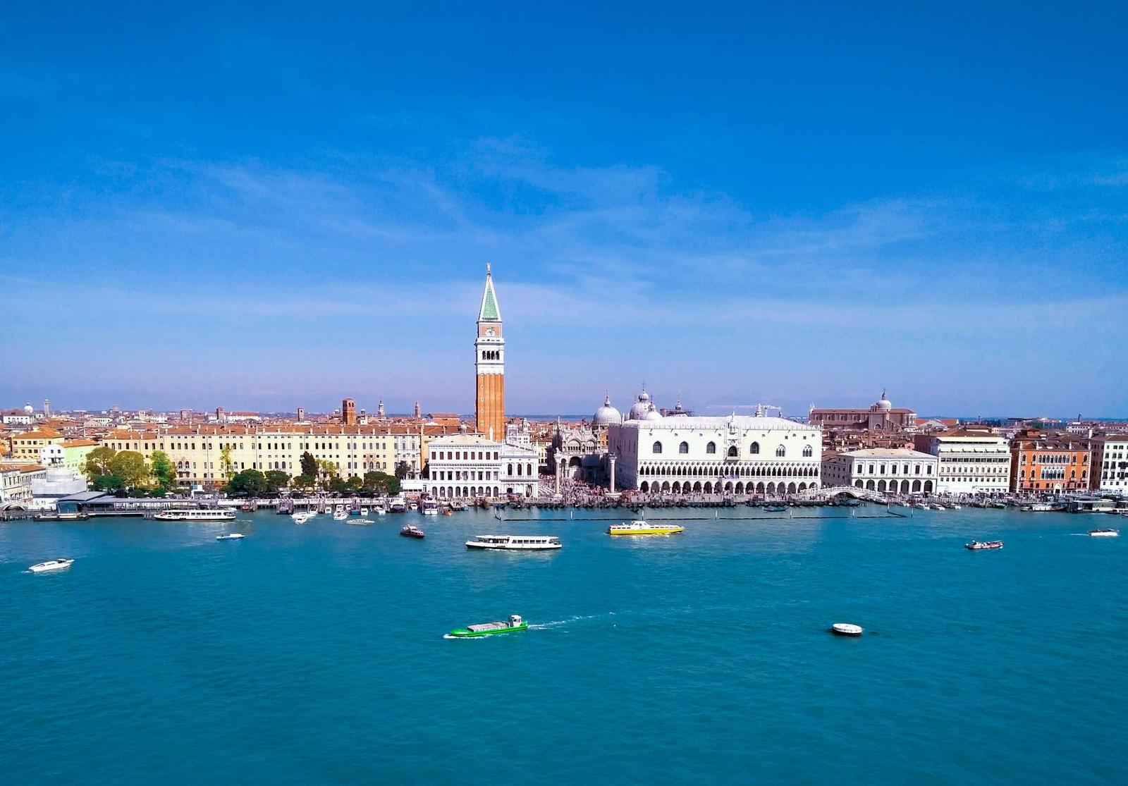 Aerial view of a lagoon city with a bell tower and boats on the water