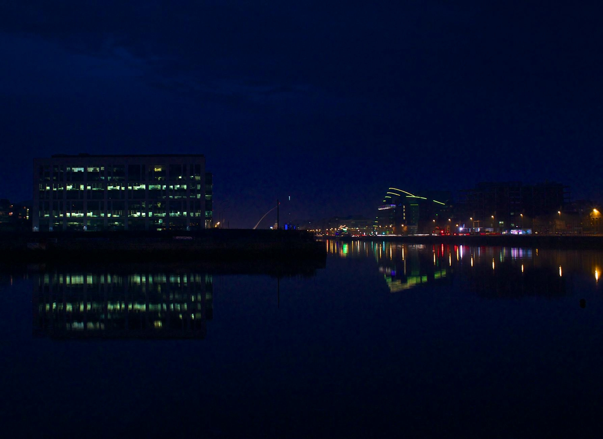 Office buildings reflected in a dark harbour at night