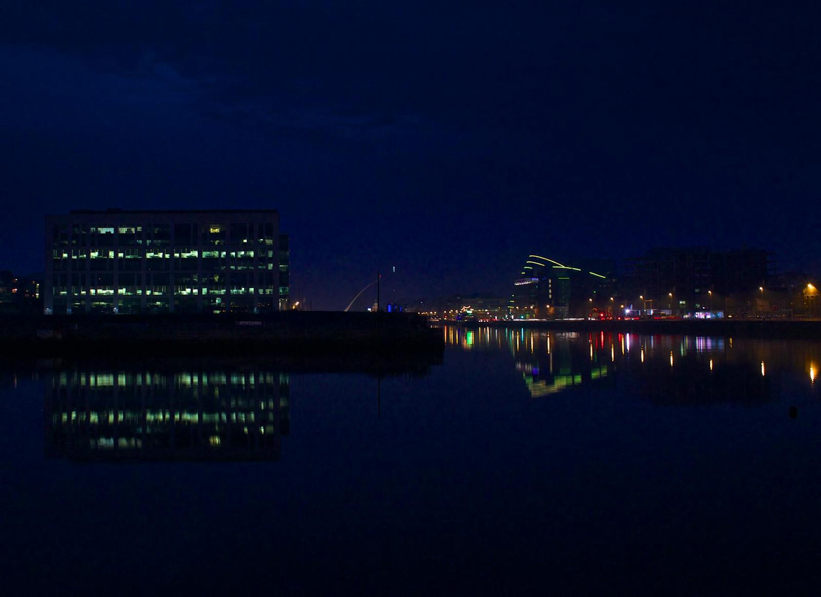 Office buildings reflected in a dark harbour at night