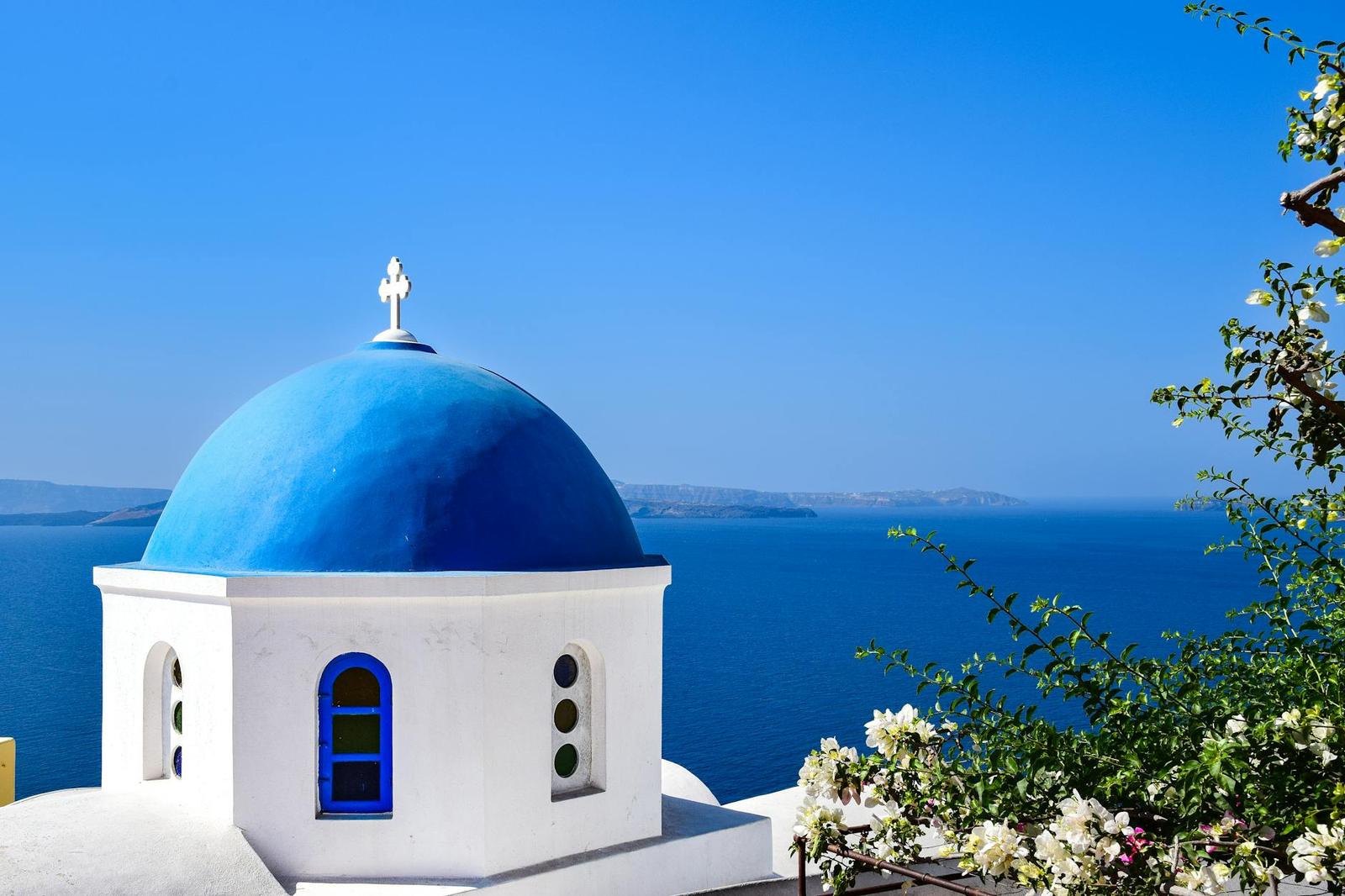 Stunning view of a blue domed church overlooking the Aegean Sea in Santorini, Greece