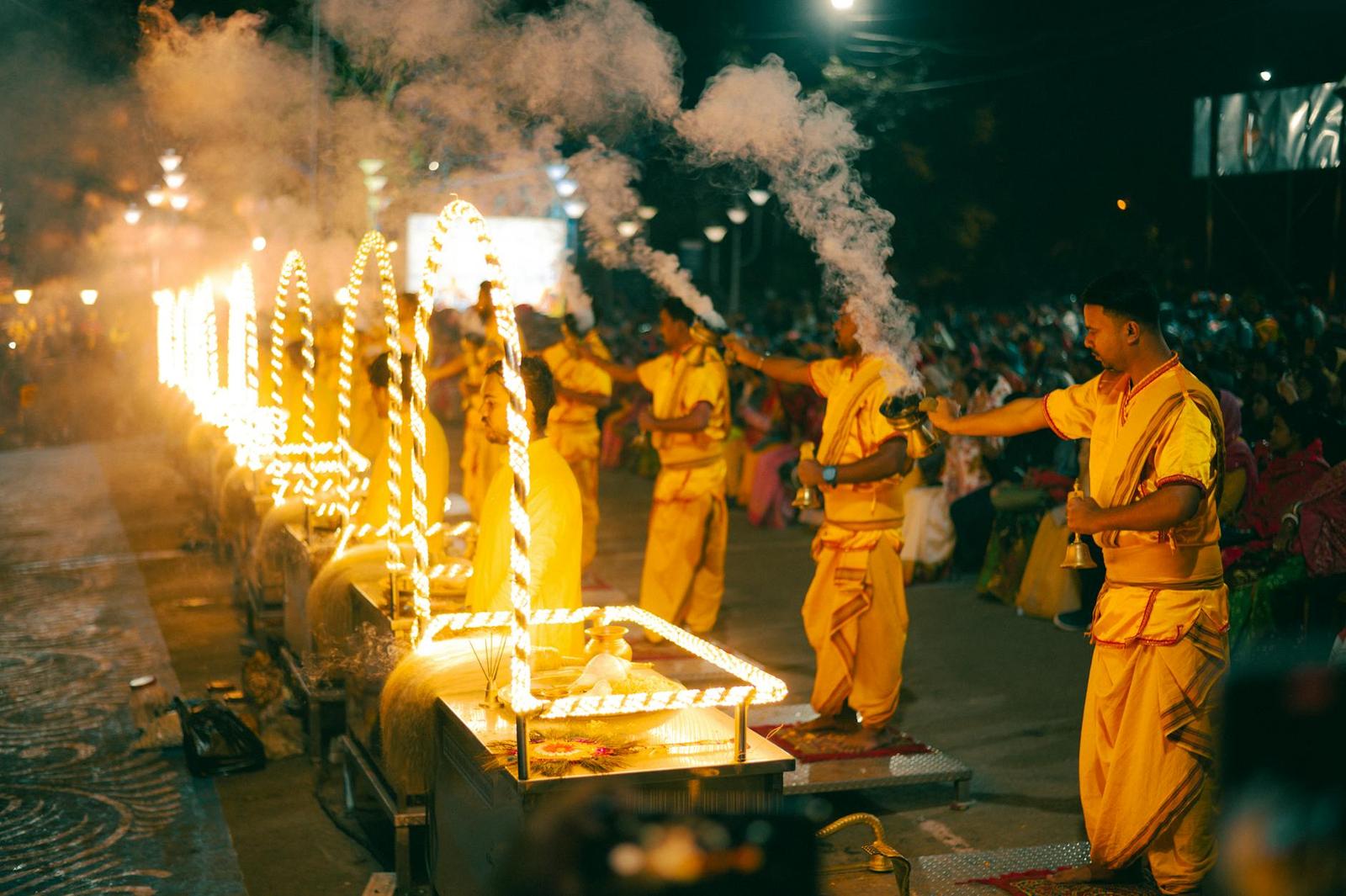 Robed priests wave flaming lamps in a night fire ritual before a crowd