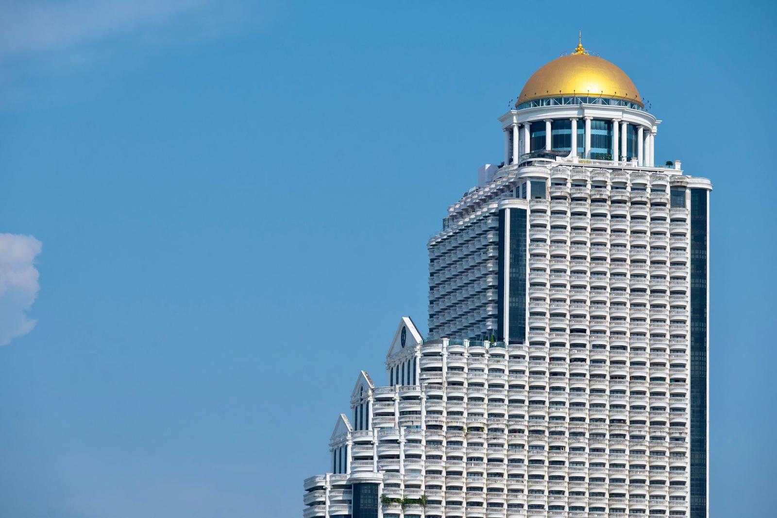 A high-rise tower topped with a golden dome under a clear blue sky