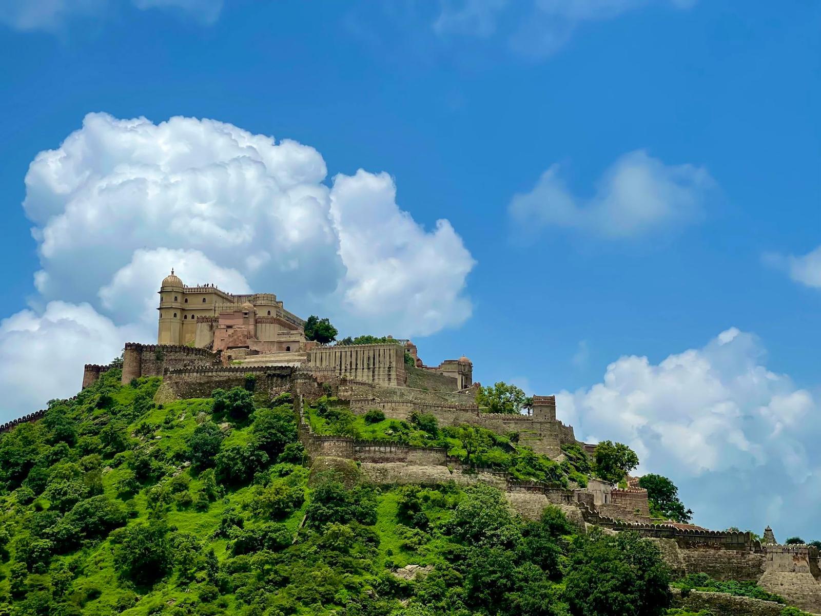 A hilltop fort with stone ramparts rising above green forest
