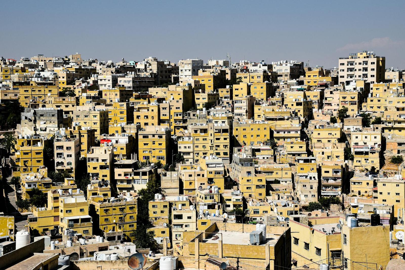 A dense hillside city of pale stone buildings under a clear sky