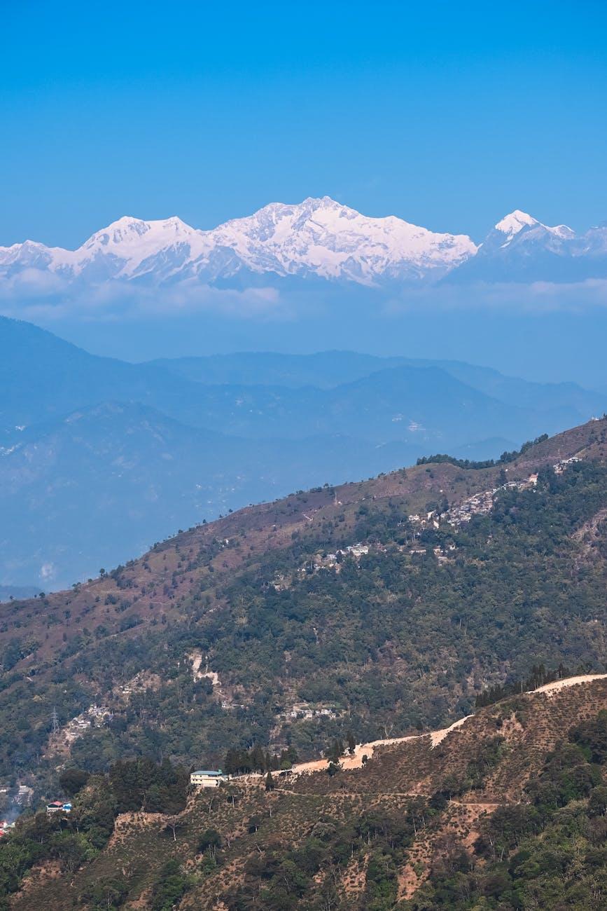Snow-capped Himalayan peaks rising above layered green hills