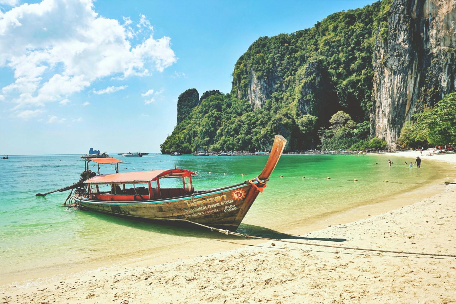 Idyllic Krabi beach scene with a traditional longtail boat and stunning limestone cliffs