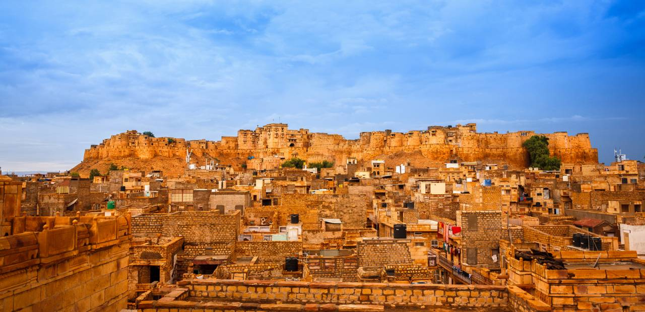 A golden hilltop fort rising above a dense sandstone old town
