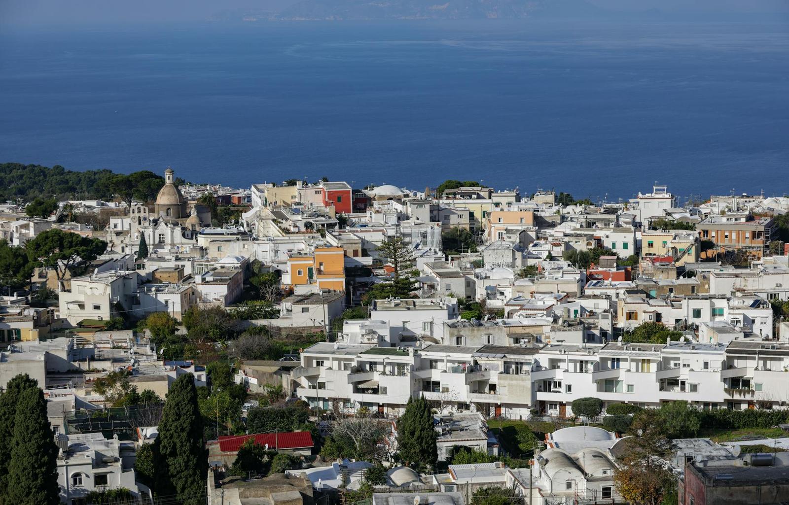 White hillside town overlooking a deep blue sea with a domed church