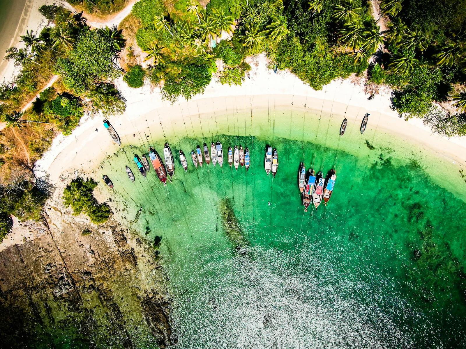 Aerial view of longtail boats moored on a shallow turquoise cove