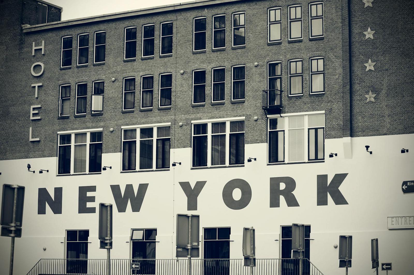 A brick building with large painted lettering reading hotel and new york on its facade