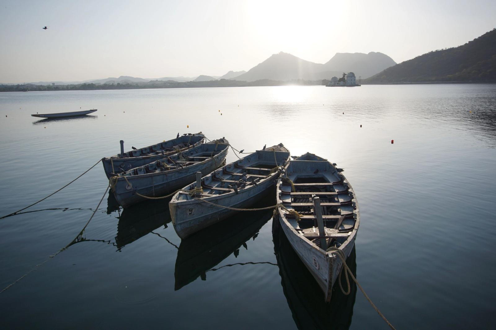 Tranquil scene of boats on Lake Pichola, Udaipur with sunrise backdrop