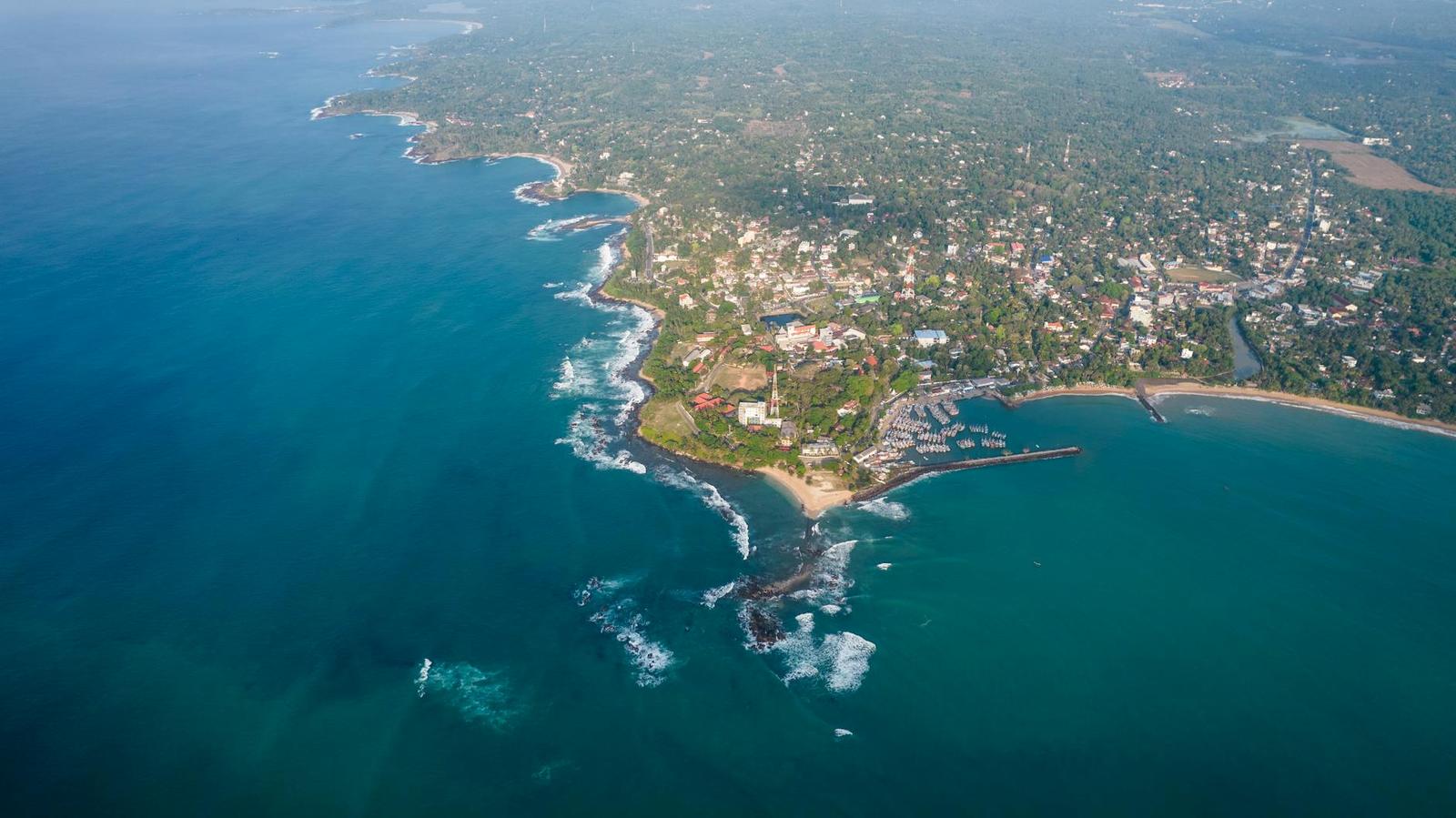 Aerial view of a wooded coastal headland surrounded by blue sea