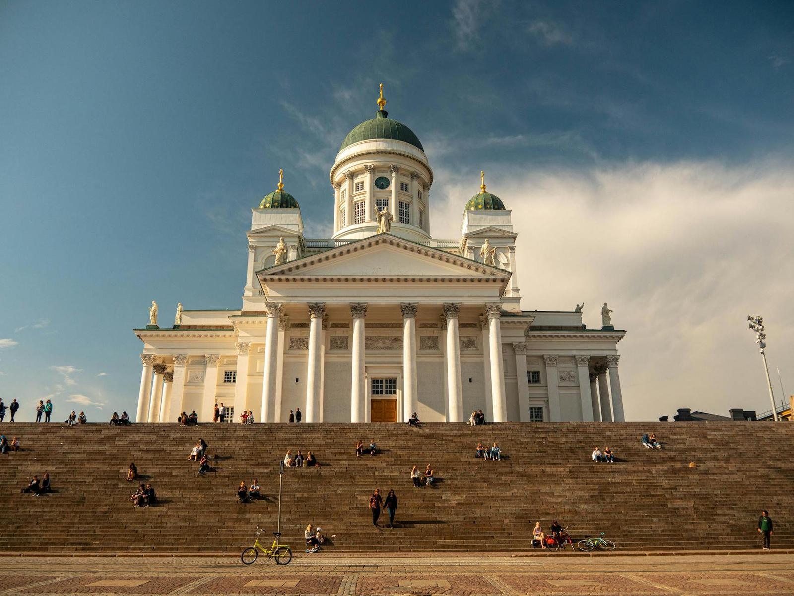 Helsinki Cathedral in Finland with people relaxing on the steps under a clear blue sky