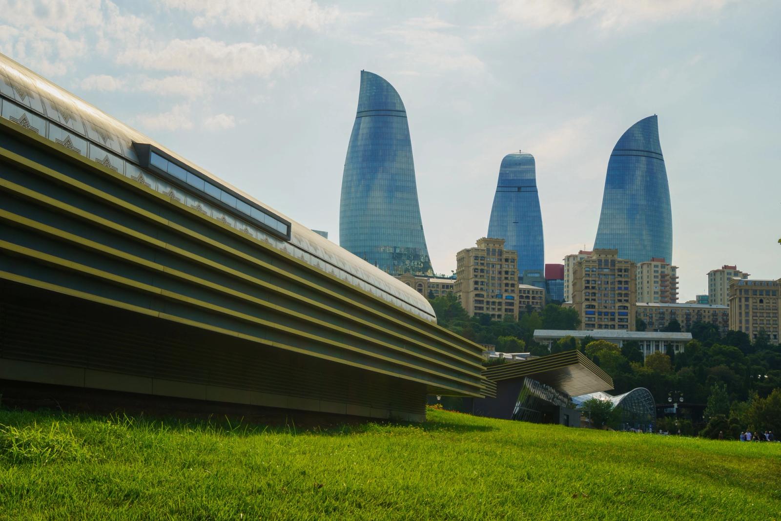 A stunning view of Baku's iconic Flame Towers set against modern architecture and lush greenery
