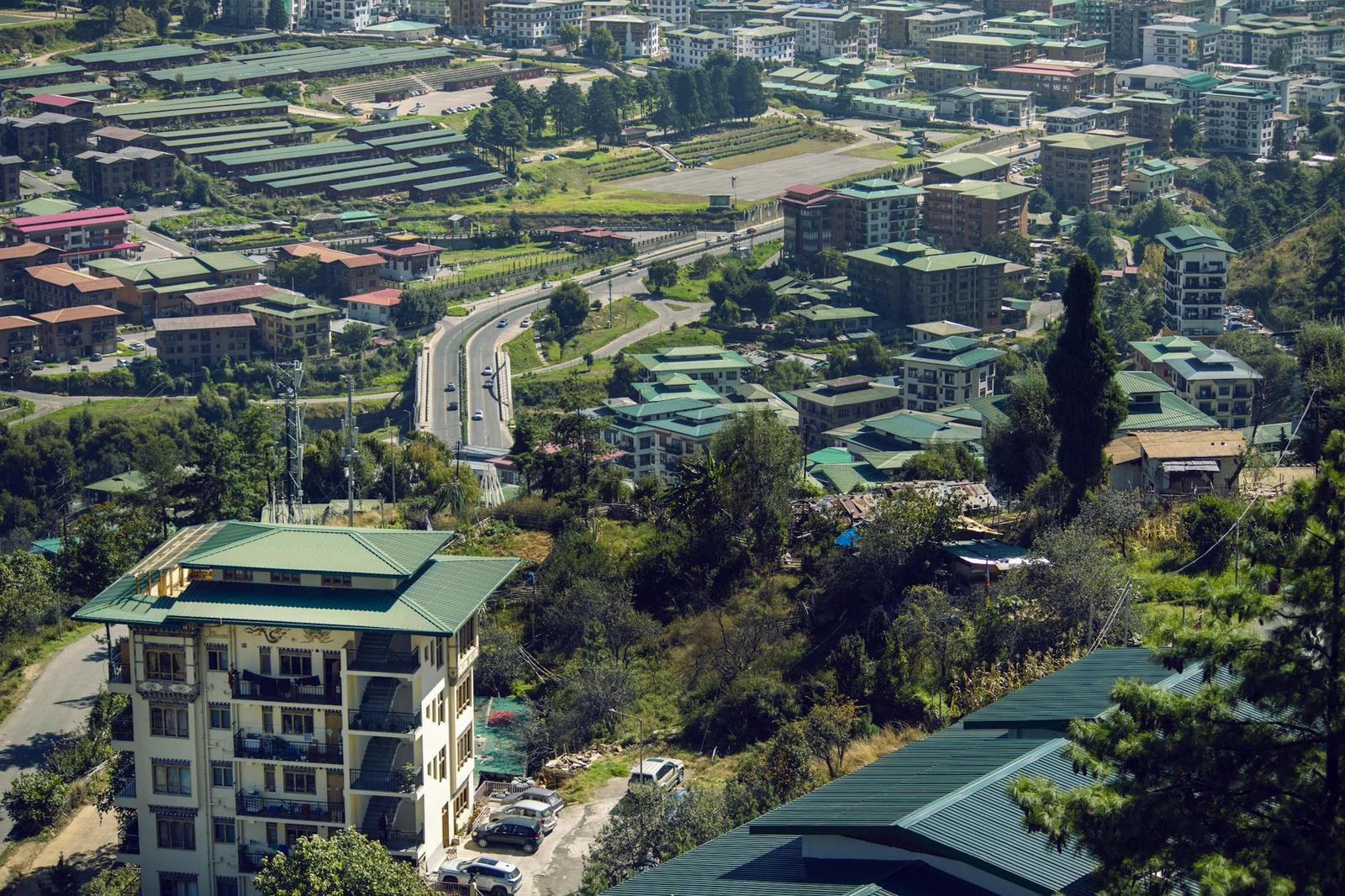 Aerial view of a hillside town with green-roofed buildings and a winding road