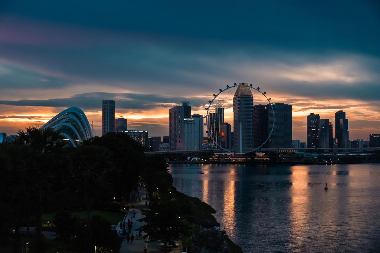A beautiful sunset view of Singapore's skyline and Ferris wheel reflecting on the water