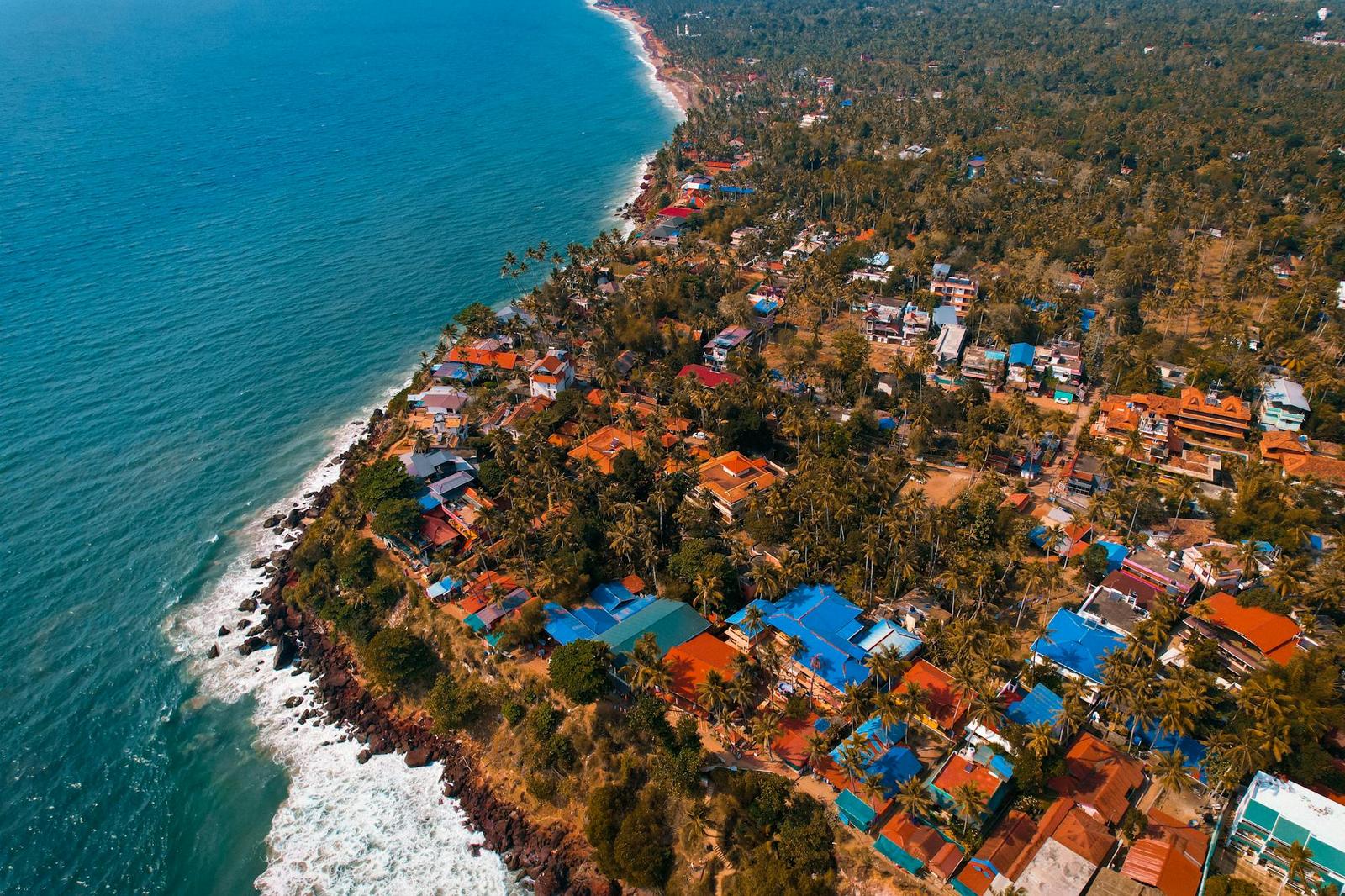 An aerial view of a coastal village with red and blue rooftops