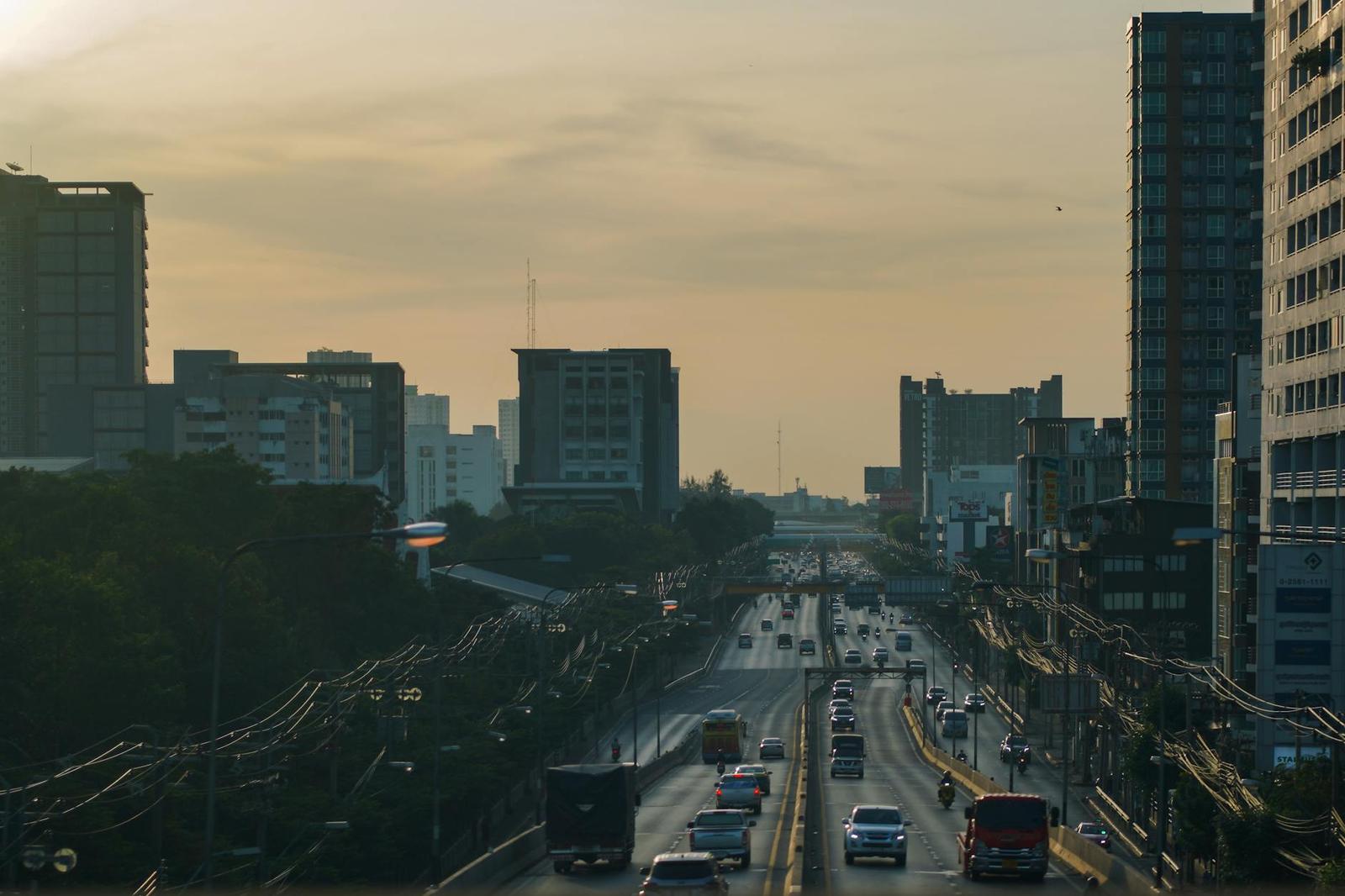 Highway traffic streaming past a city skyline at sunset