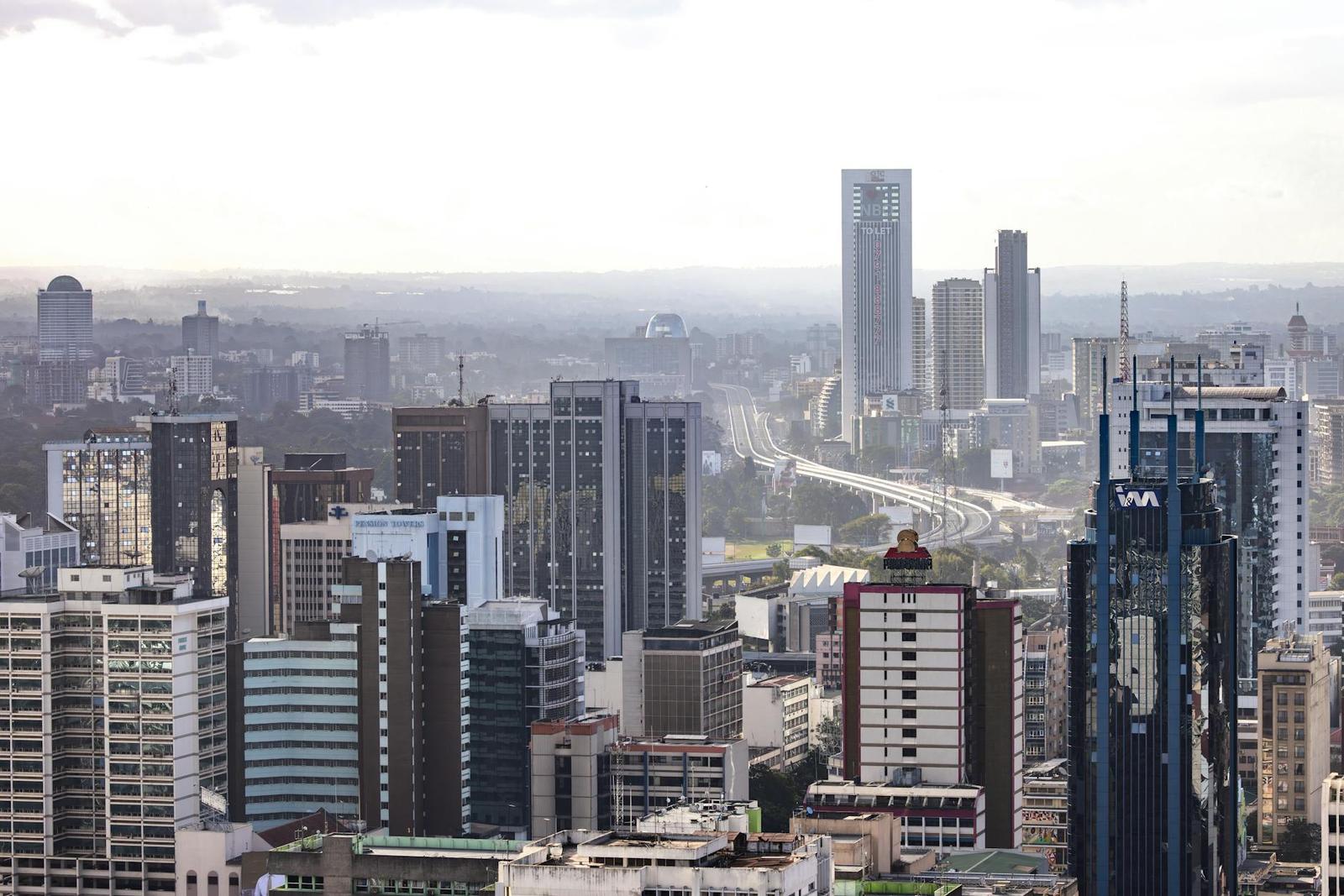 A hazy city skyline of towers and a highway seen from above