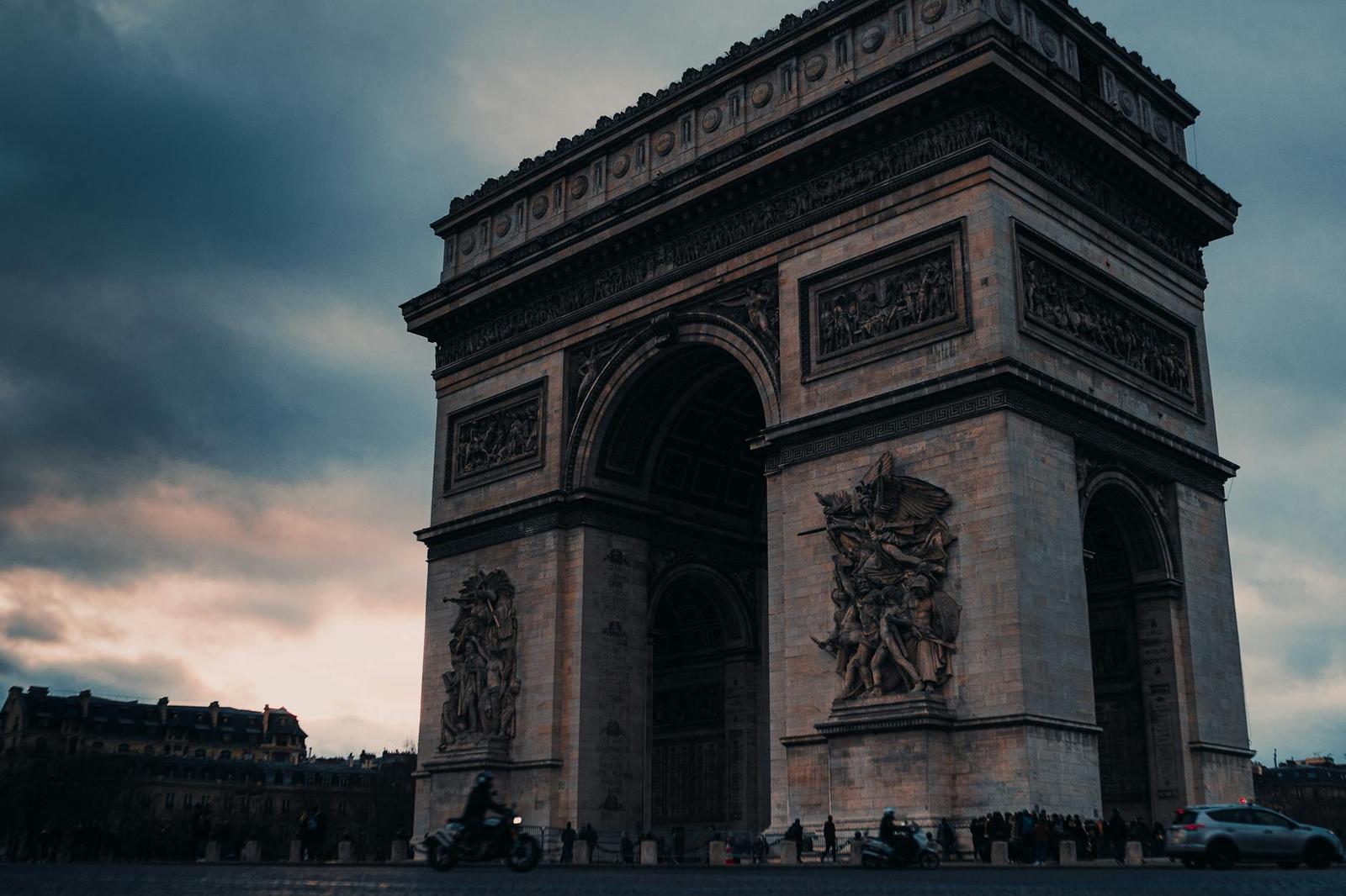 Captivating view of the Arc de Triomphe at dusk in Paris, France, under a dramatic sky
