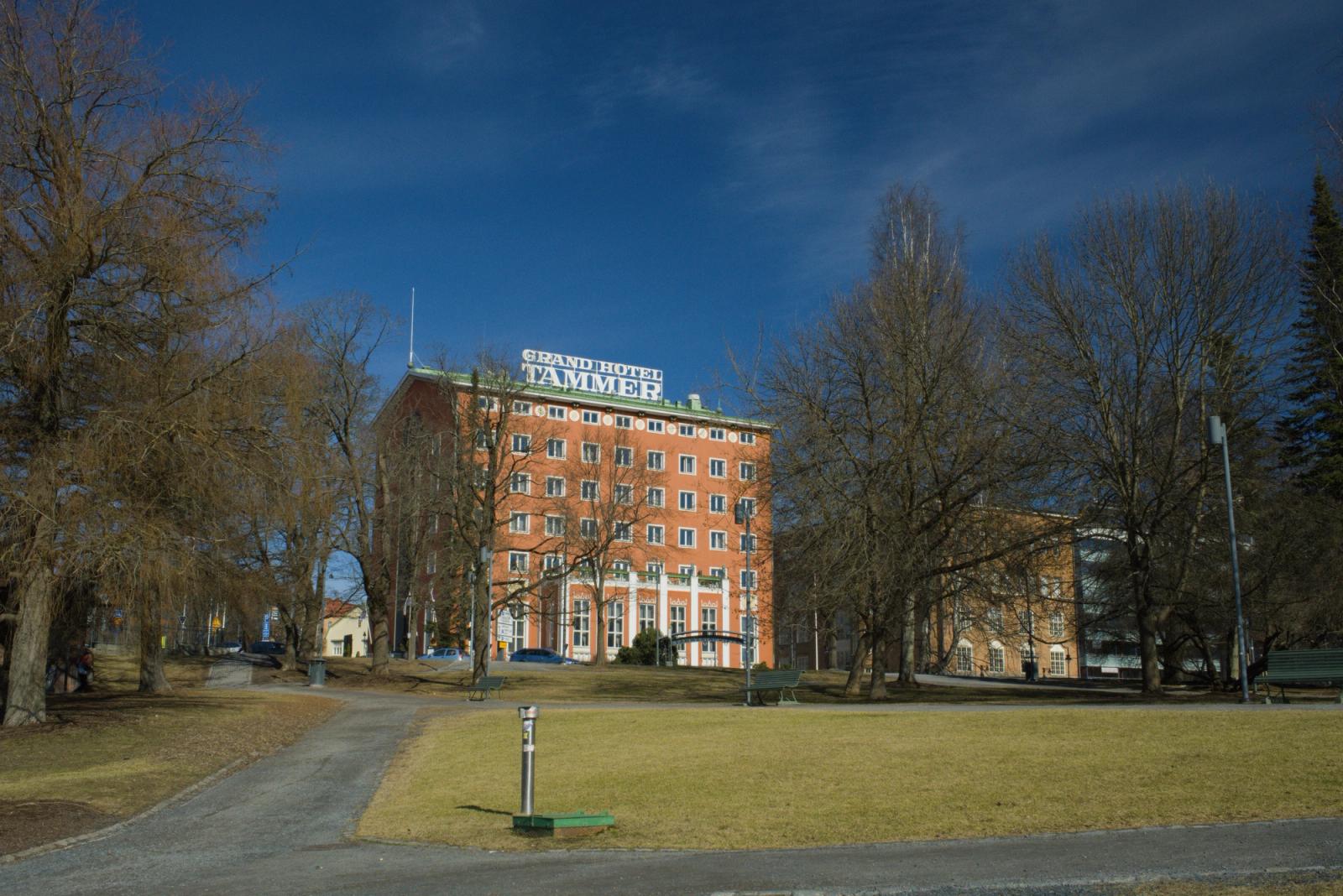 Front view of Grand Hotel Tammer surrounded by trees on a sunny day in Tampere, Finland