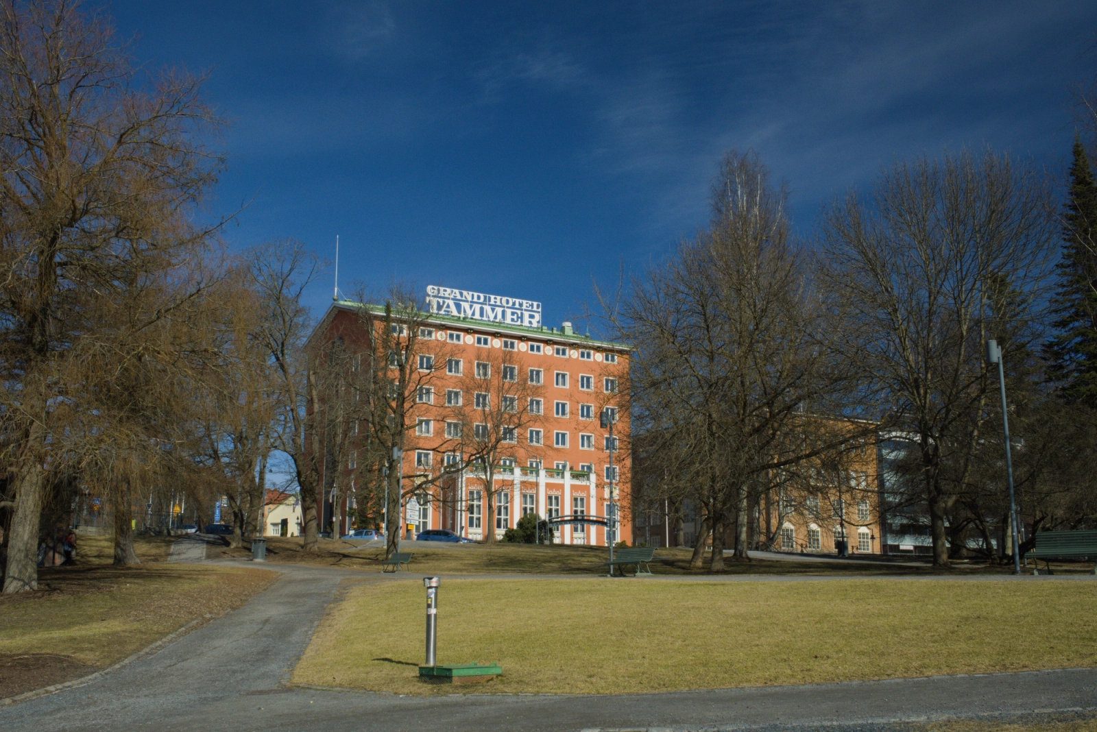 Front view of Grand Hotel Tammer surrounded by trees on a sunny day in Tampere, Finland