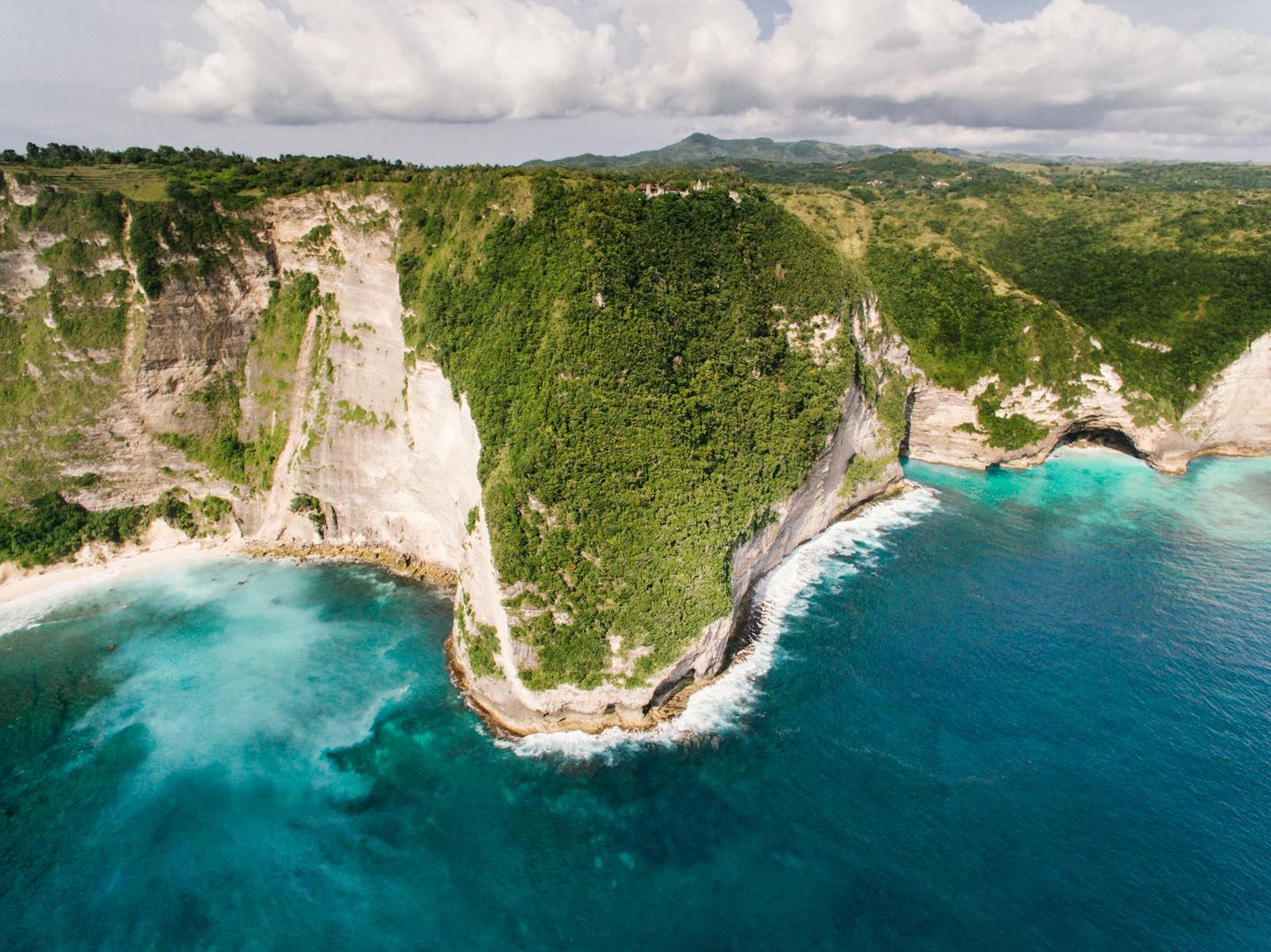 Aerial view of a turquoise cove framed by tall limestone cliffs