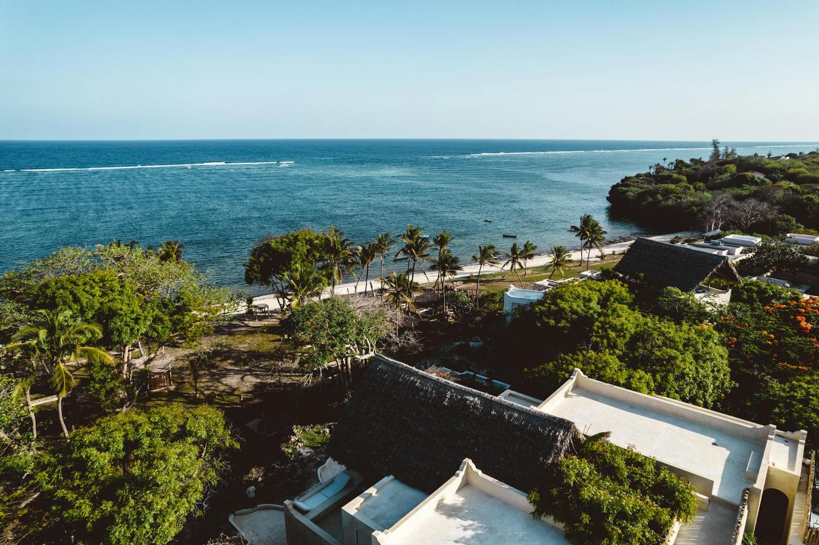 An aerial view of a beachfront resort surrounded by palms and coastal scrub
