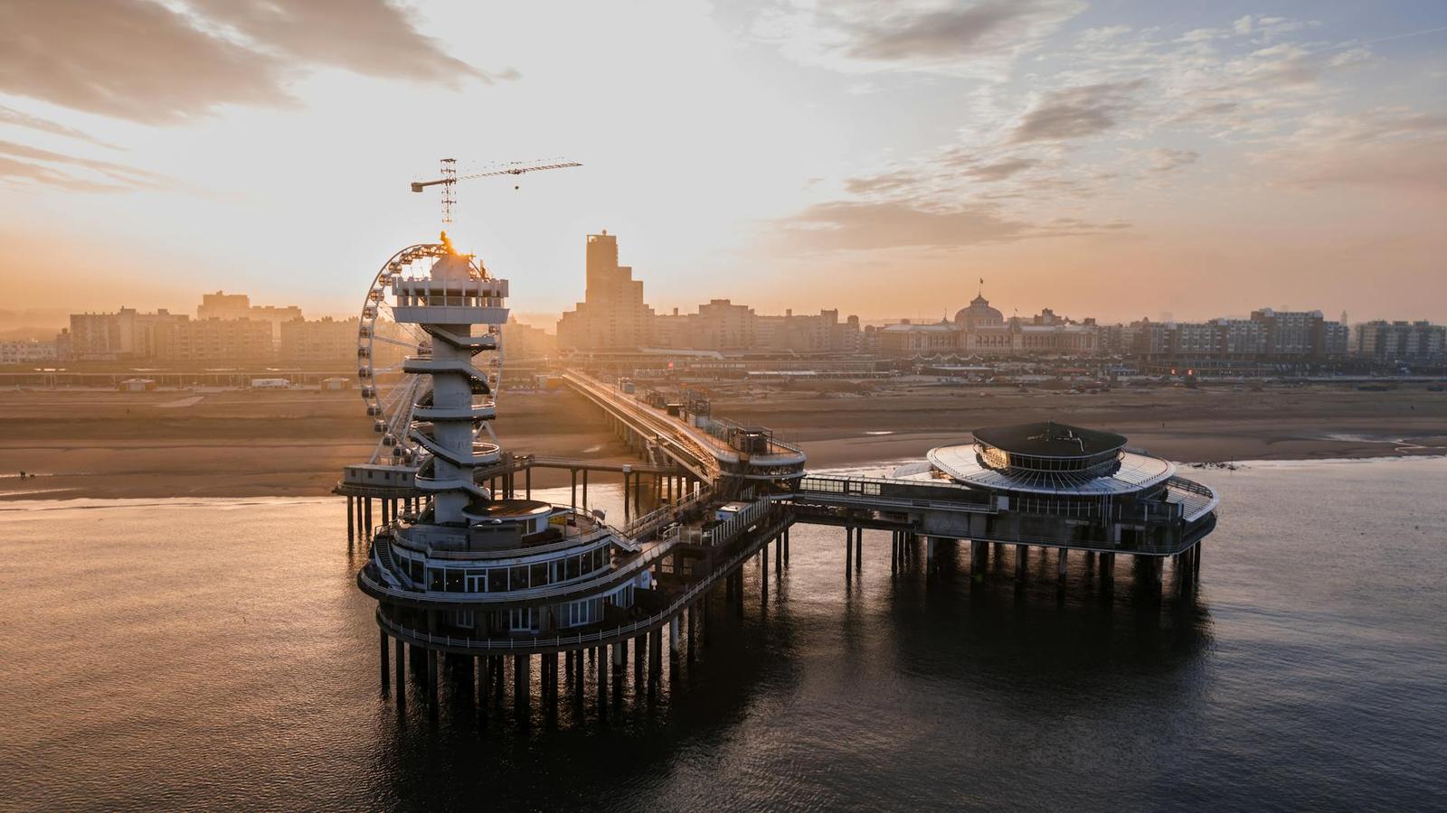 Aerial view of a seaside pier with an observation wheel at sunset