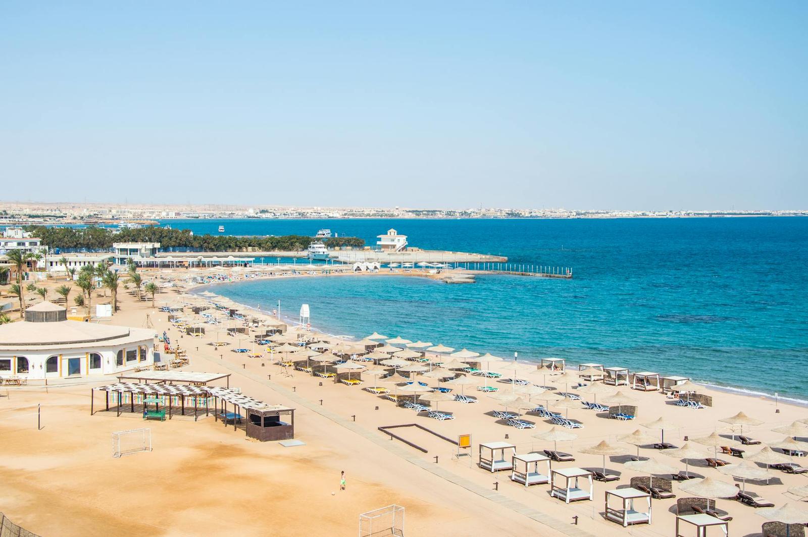 Aerial view of a resort beach with sun loungers along a turquoise bay