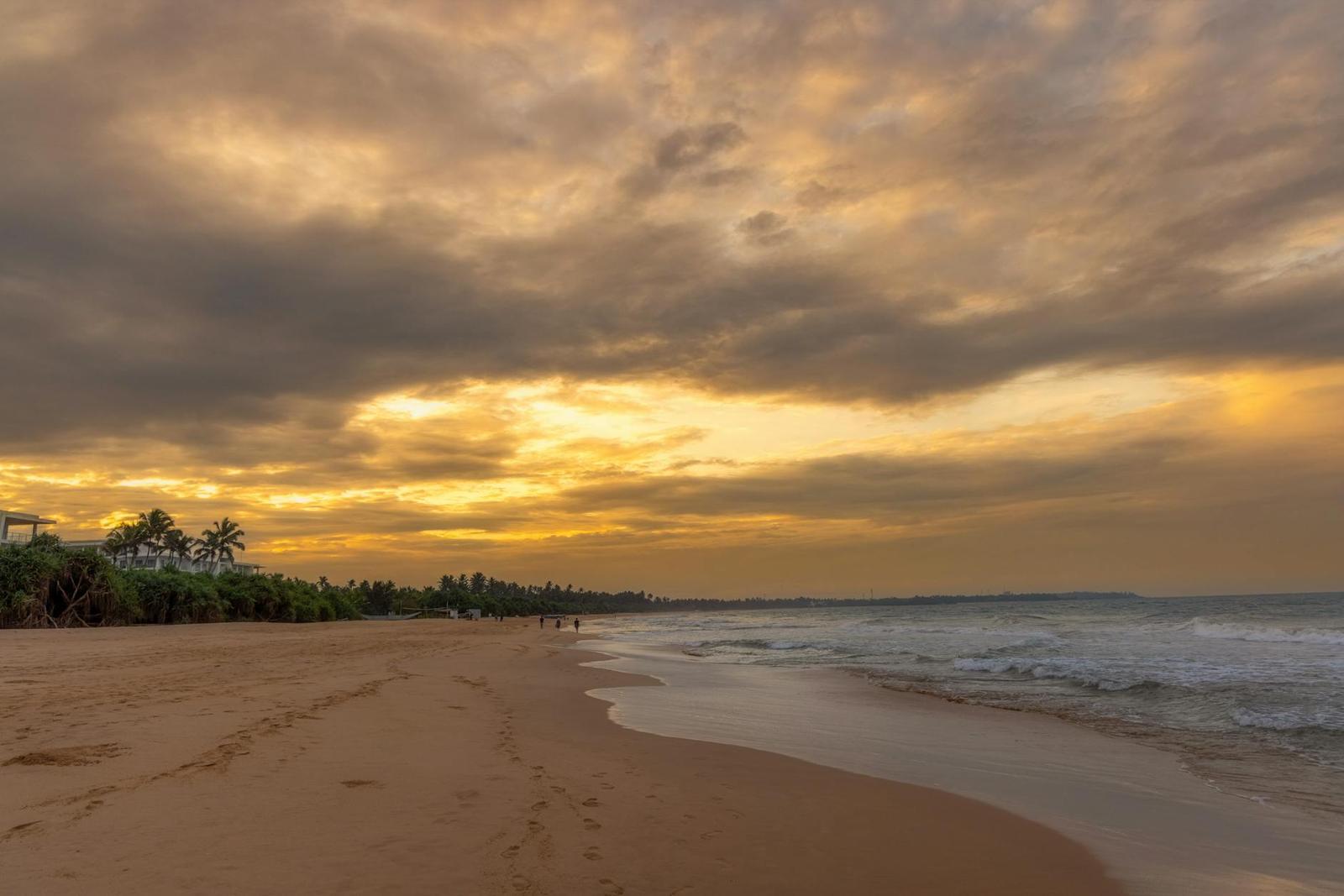Serene sunset view over Bentota Beach and coastline in Sri Lanka, featuring golden skies and calm waves