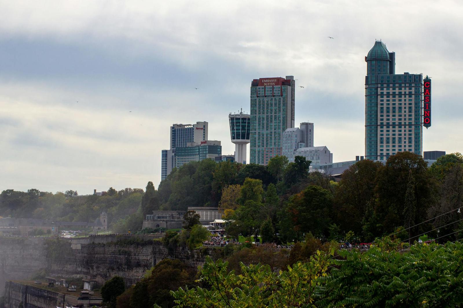 Hotel towers on a wooded bluff rising above mist from a waterfall below