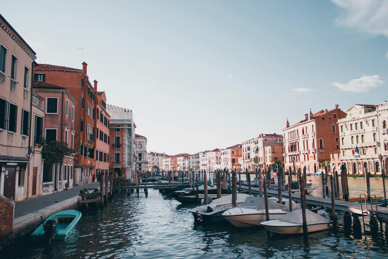 Small boats moored along a wide canal lined with pastel waterfront buildings