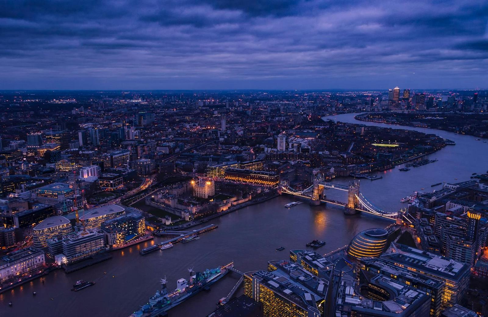 An aerial night view of a lit river crossing winding through a city skyline