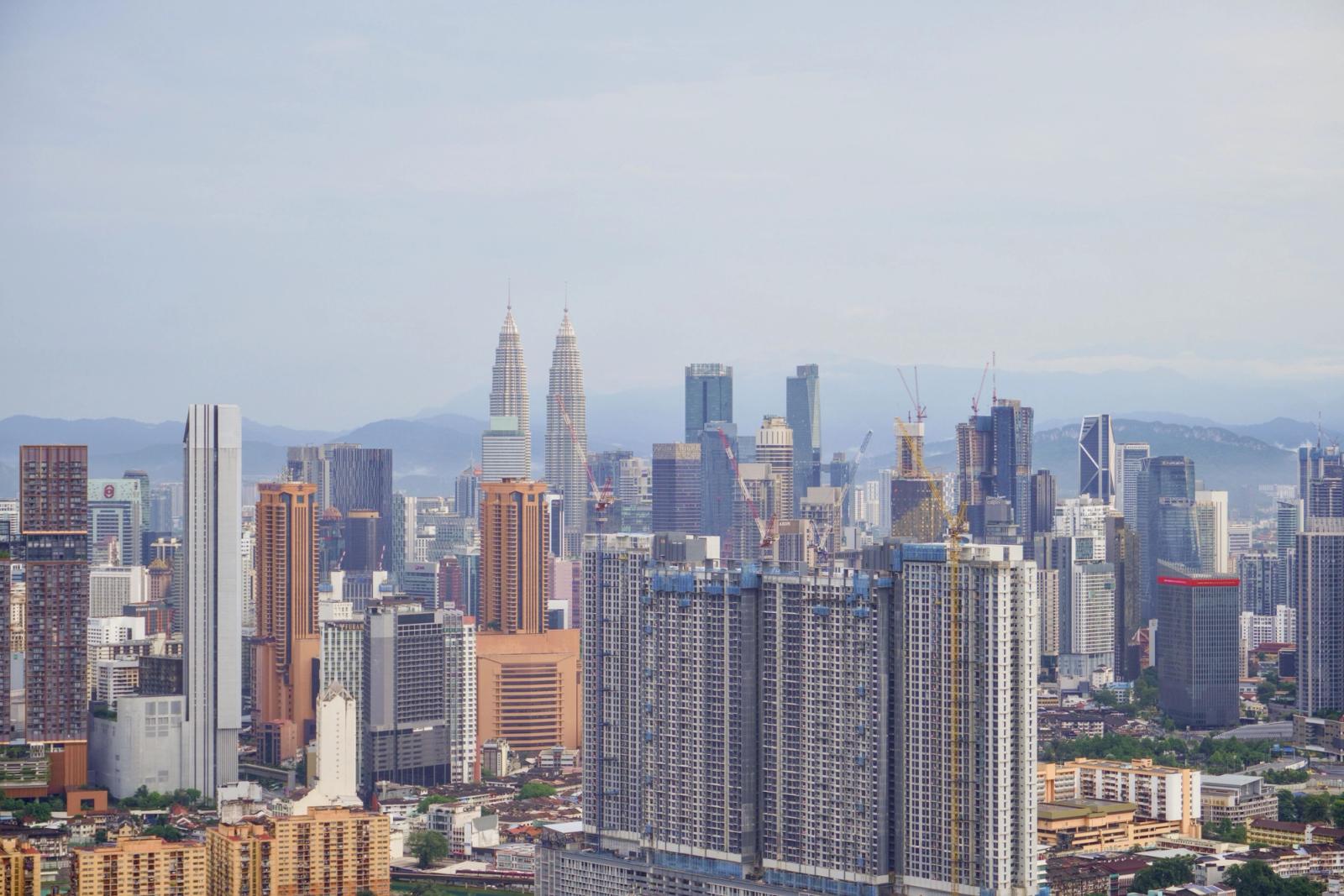 Aerial view of Kuala Lumpur's skyline with iconic Petronas Towers under a clear blue sky