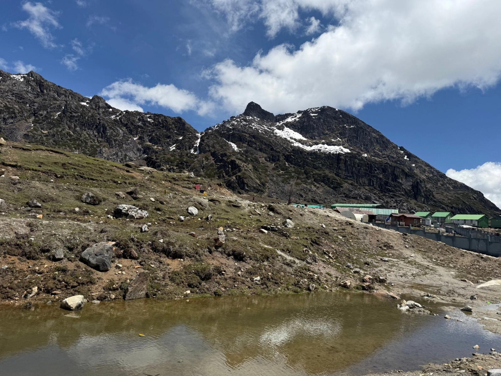 Beautiful mountain landscape in Tawang, India with snow-capped peaks and a tranquil pond under blue skies